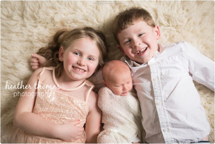 Welcome Miss G \ Yardley, PA Newborn Photographer Newborn Session with Siblings holding their sister at a photography studio in bucks county pa photo by heather thomas photography