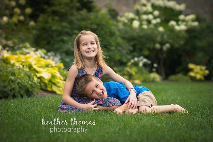 Family Photography at Bryn Athyn in Philadelphia siblings laying in the grass laughing at the camera in montgomery county