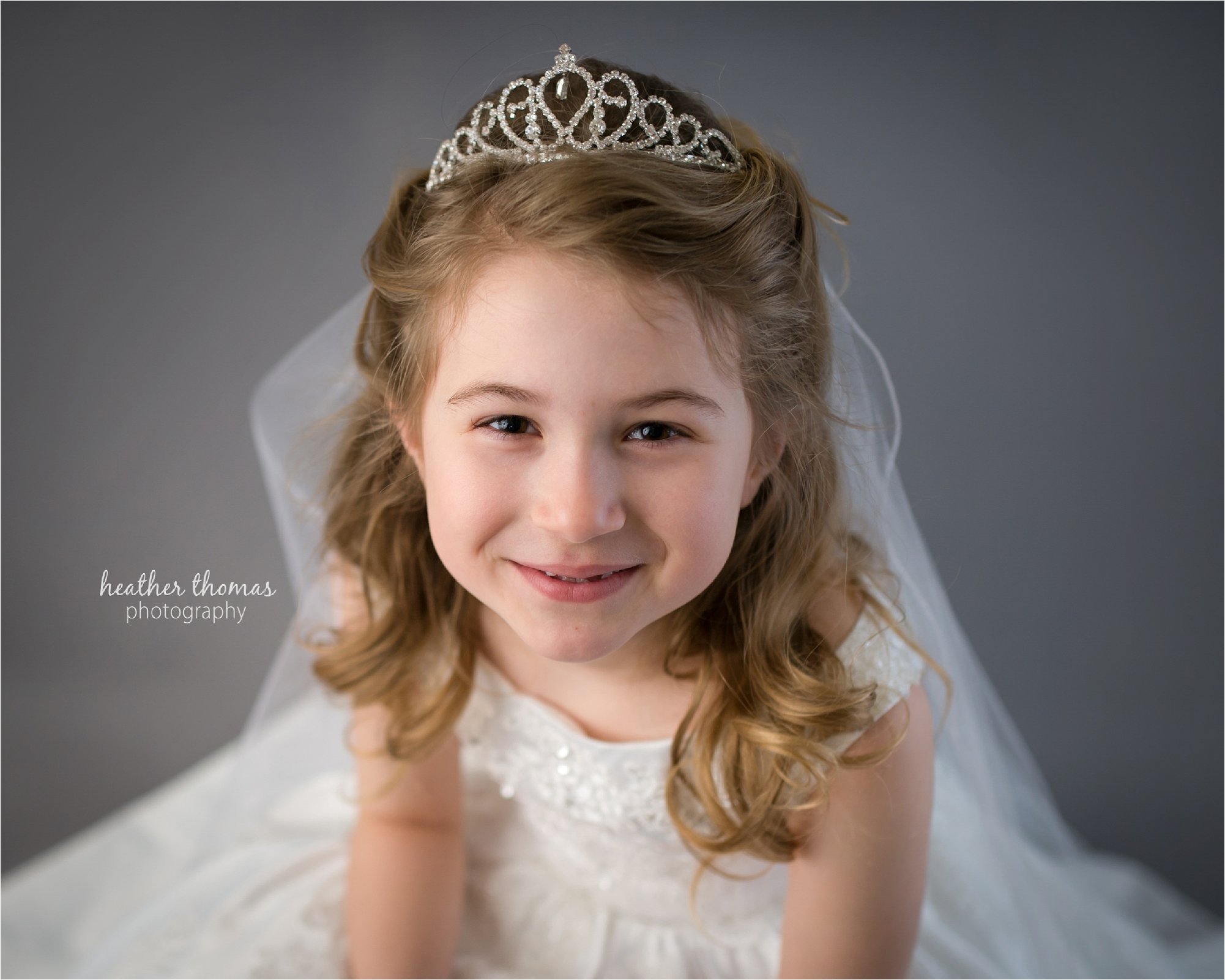 an 8 year old girl smiling at the camera at the heather thomas photography studio in netown maternity portraits of a family of three at azalea garden waterworks with heather thomas photography
