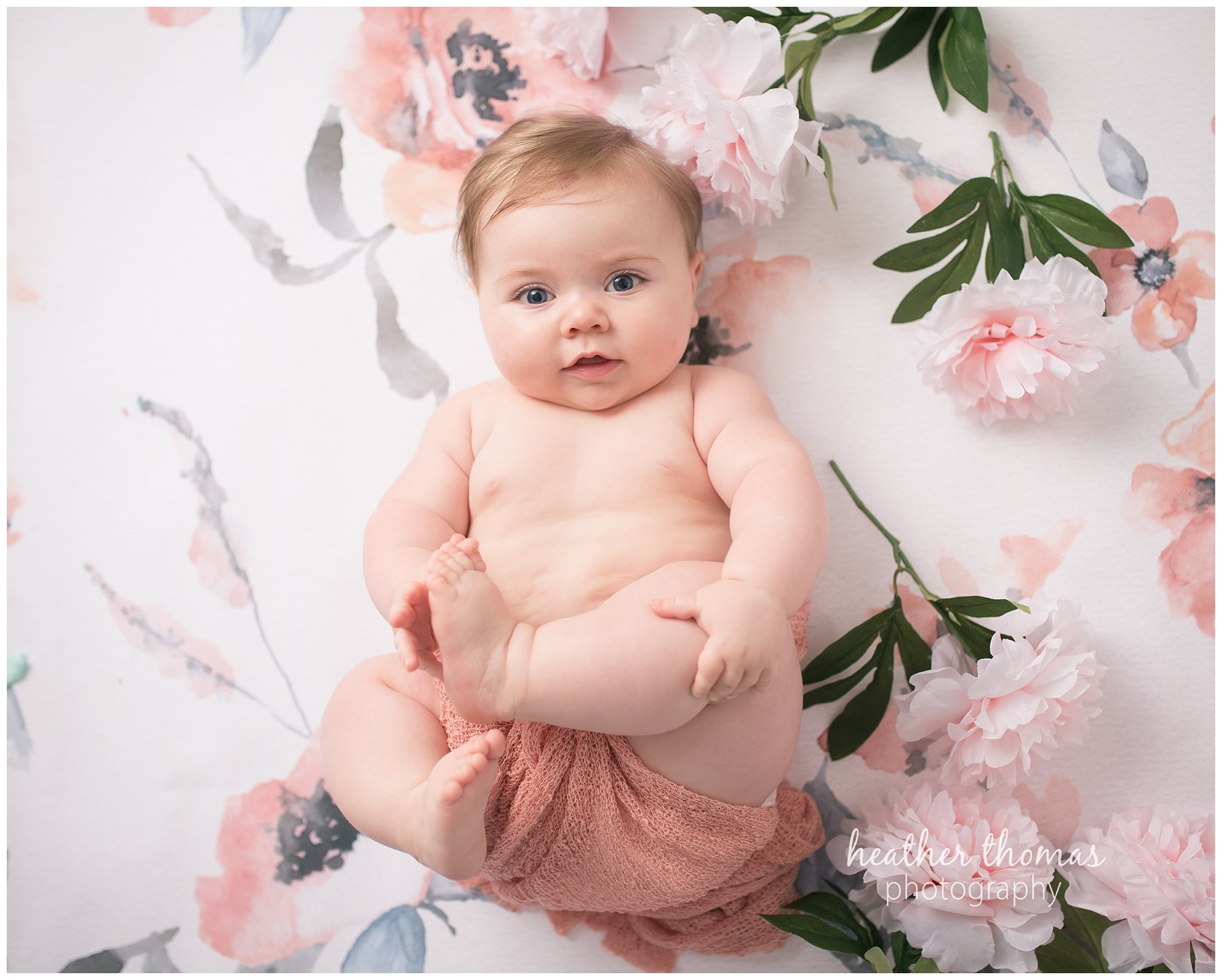 baby photo shoot philadelphia-14.jpg a 7 month old looking at the camera sitting laying on her back on a pink backdrop in newtown pa