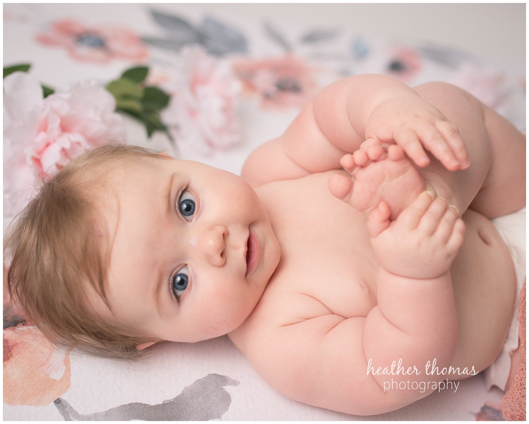 baby photo shoot philadelphia-17.jpg an infant holding her toes smiling at the camera at her photo shoot with heather thomas photography