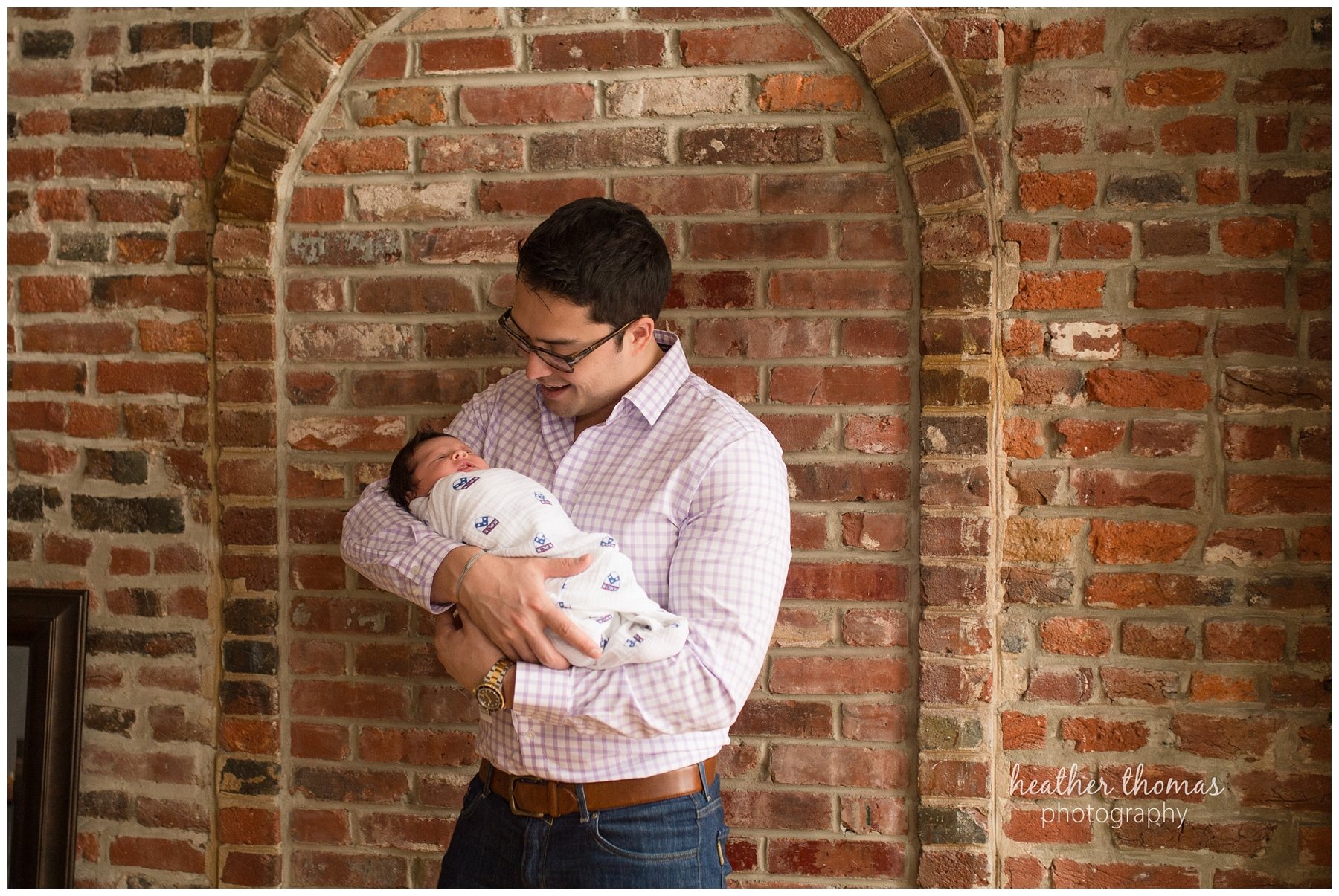 philadelphia lifestyle portraits-62.jpg a father holding his newborn baby in a university of Pennsylvania blanket at his home in philadelphia