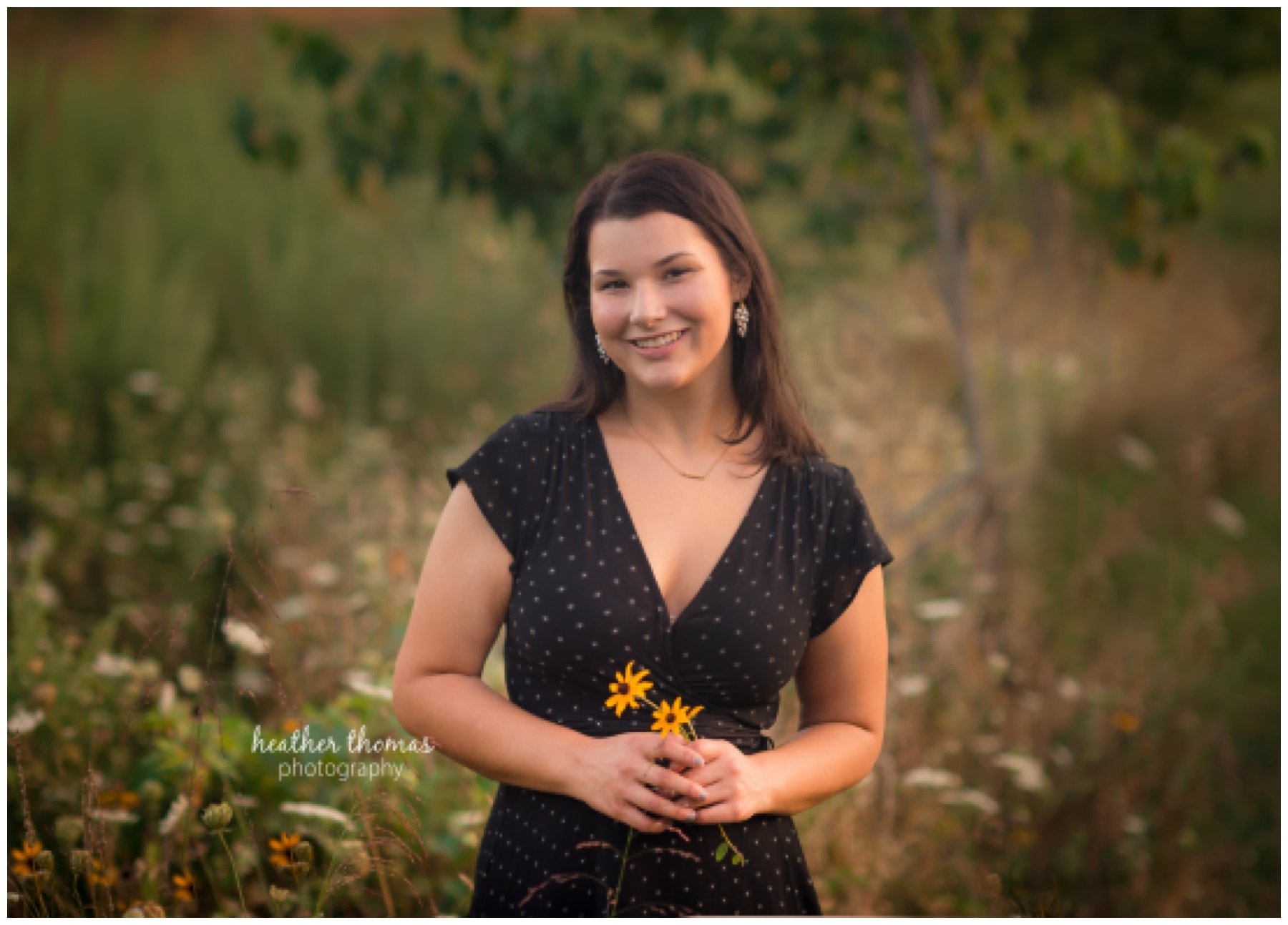 Senior Pictures Philadelphia-38.jpg a senior wearing a black dress in a field holding a yellow flower for a photo shoot
