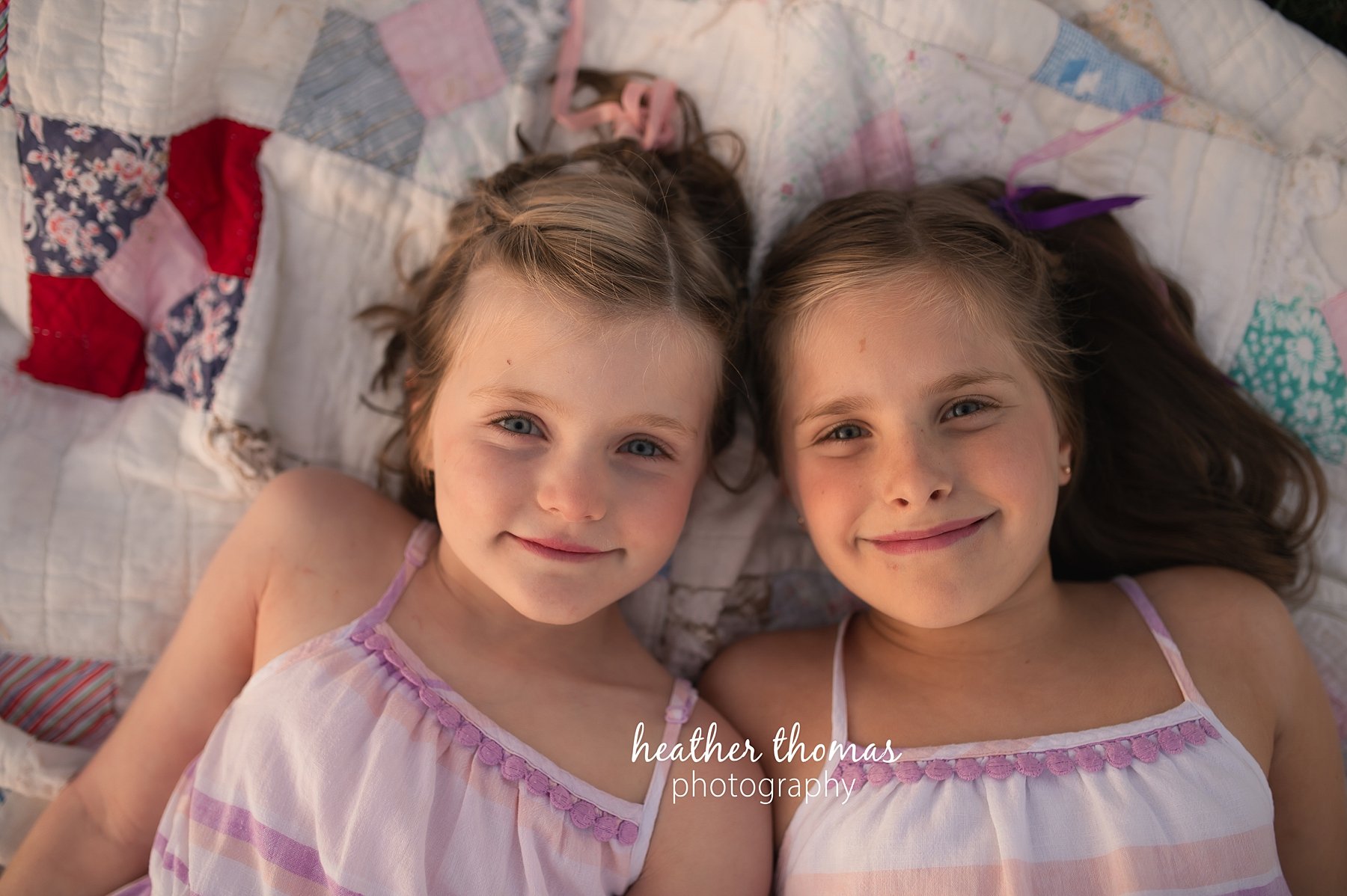 field family portraits in philadelphia a picture of two girls laying on a blanket outside at a field in Philadelphia with heather thomas photography