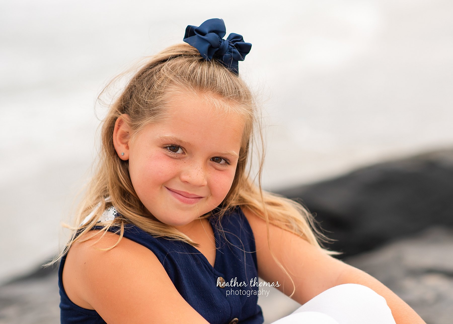 a family photo shoot in ocean city nj a closeup picture of a girl sitting on the beach in ocean city nj at a photo session with heather thomas photography