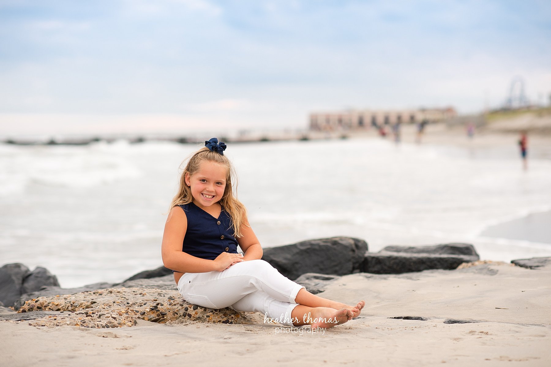 a family photo shoot in ocean city nj a picture of a girl sitting on the beach in ocean city nj at a photo session with heather thomas photography