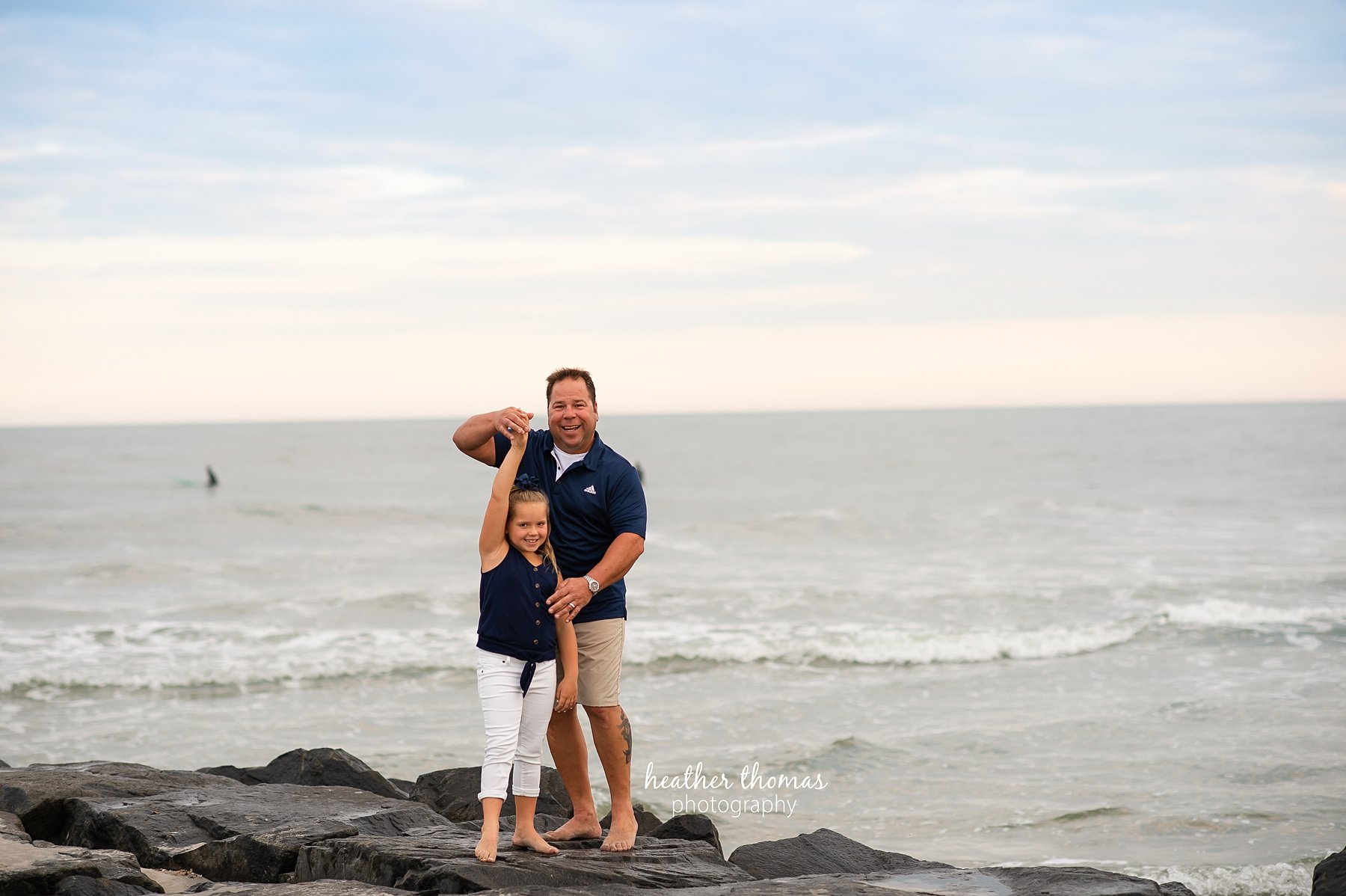 a family photo shoot in ocean city nj a dad twirling his daughter on the beach in ocean city nj at a photo shoot with heather thomas photography