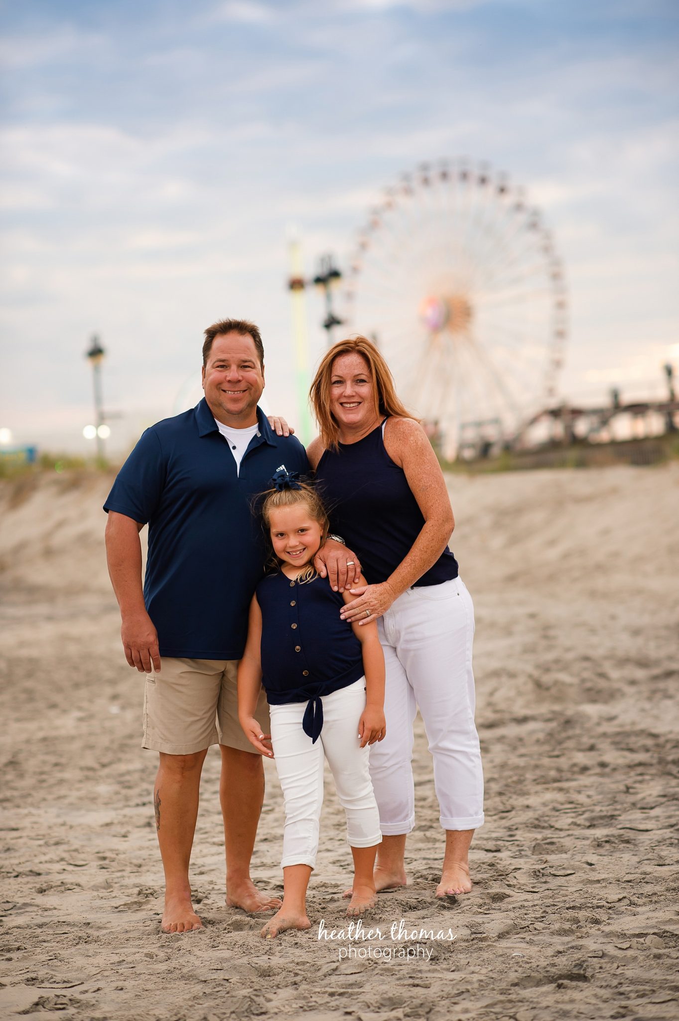 a family photo shoot in ocean city nj a picture of a family standing in front of gillians music pier at a beach portrait session with heather thomas photography