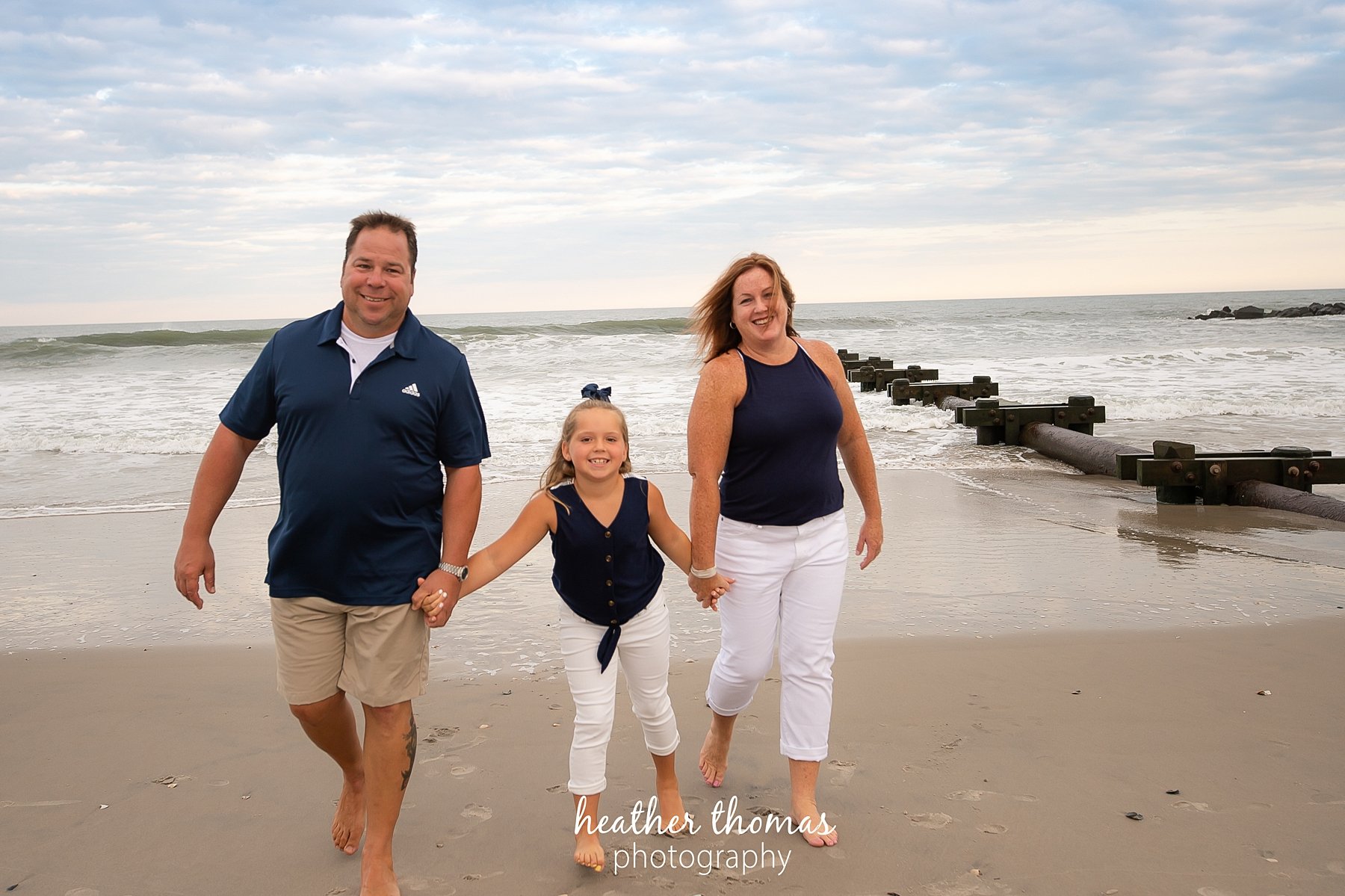 a family photo shoot in ocean city nj a family running on the beach at a portrait session with heather thomas photography