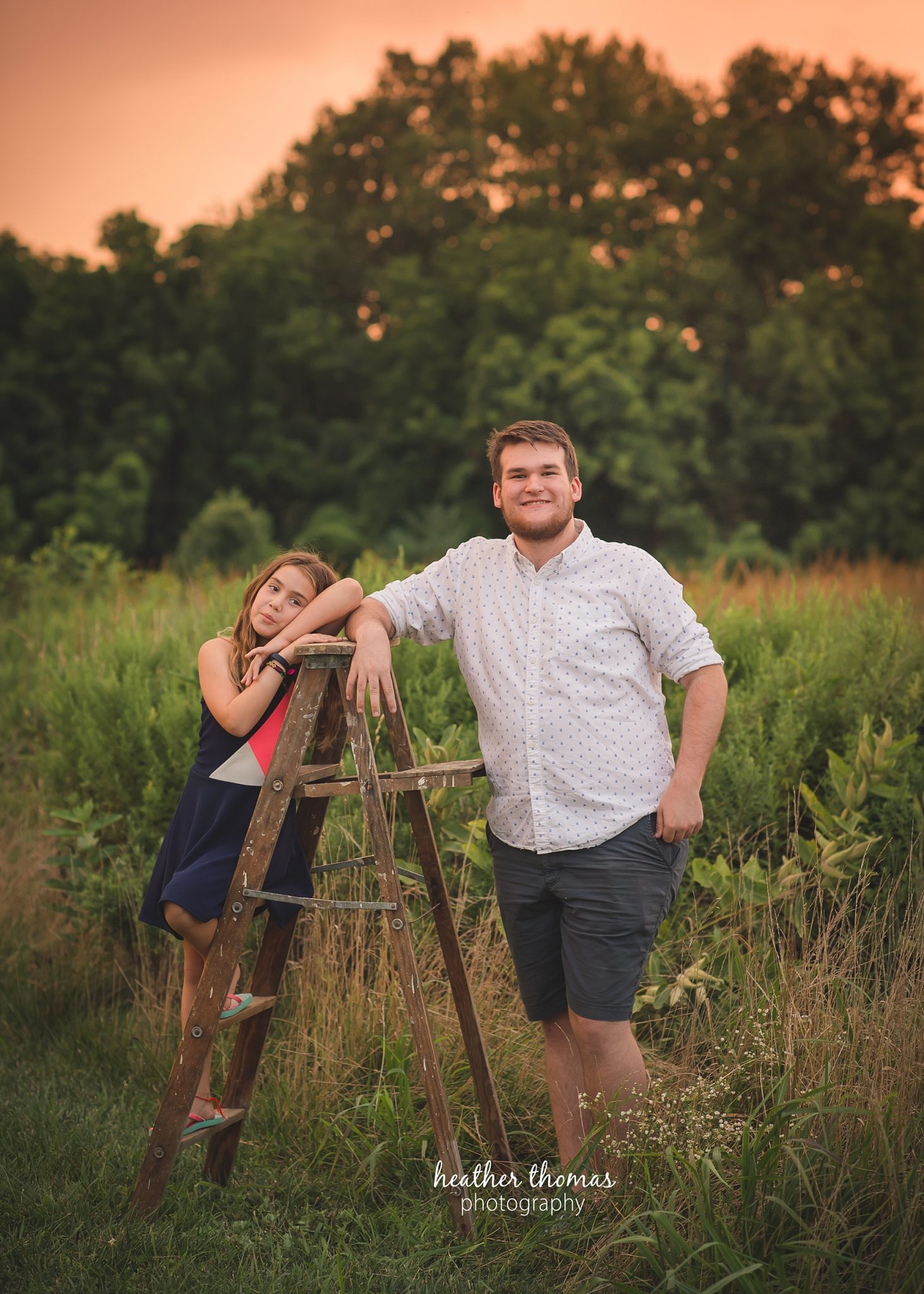 field family portraits in philadelphia a picture of a sister and her brother posing outside in a field in philadelphia with heather thomas photography