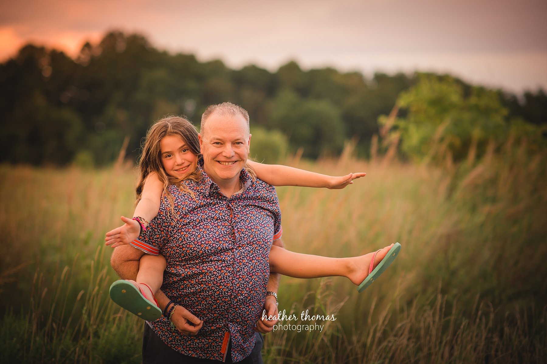 field family portraits in philadelphia a picture of a dad on her dads back outside in a field in philadelphia with heather thomas photography