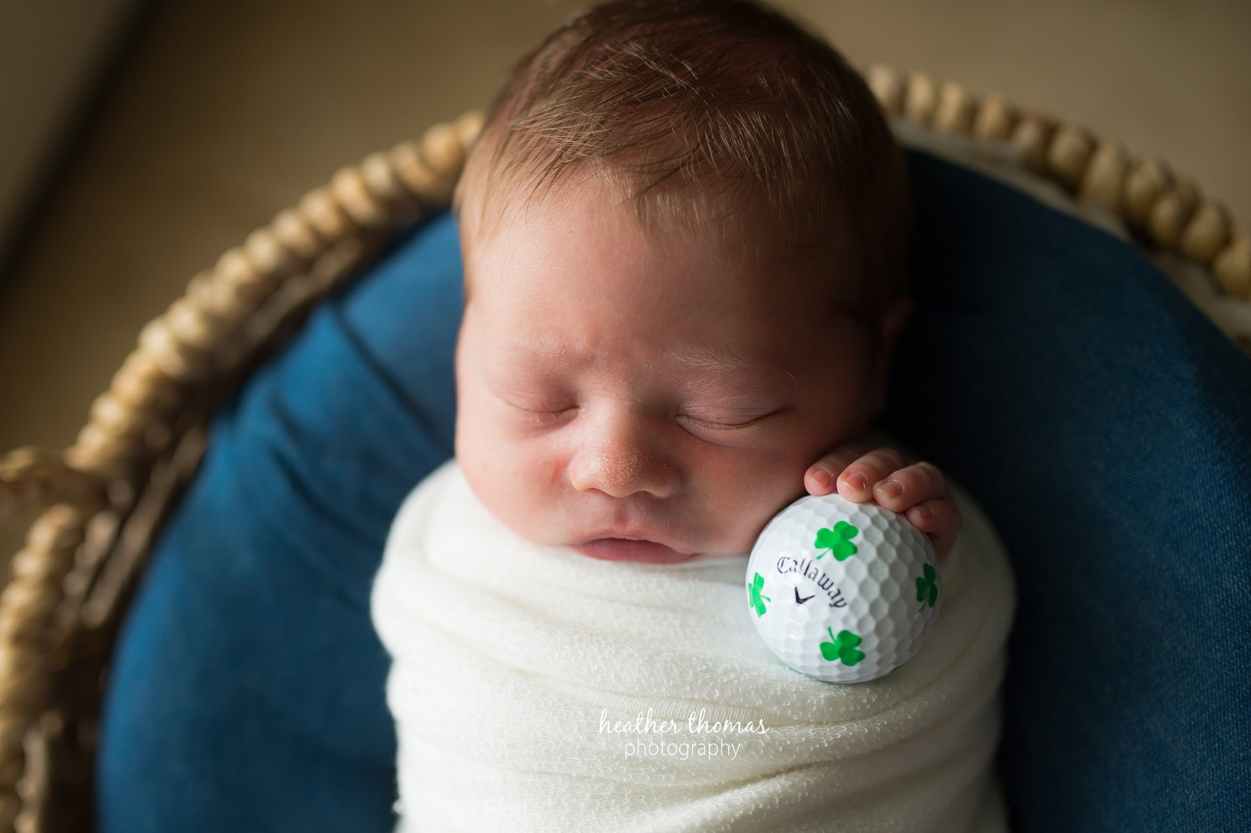 a newborn in home photo shoot in bucks county a picture of a newborn holding a callaway golf ball