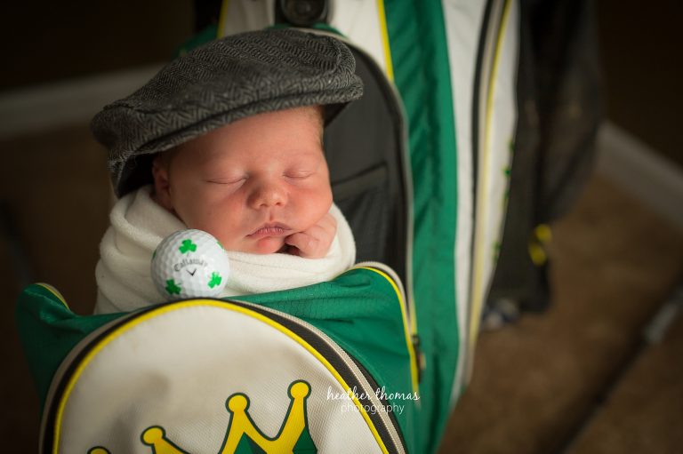 a newborn boy sitting in a golf bag