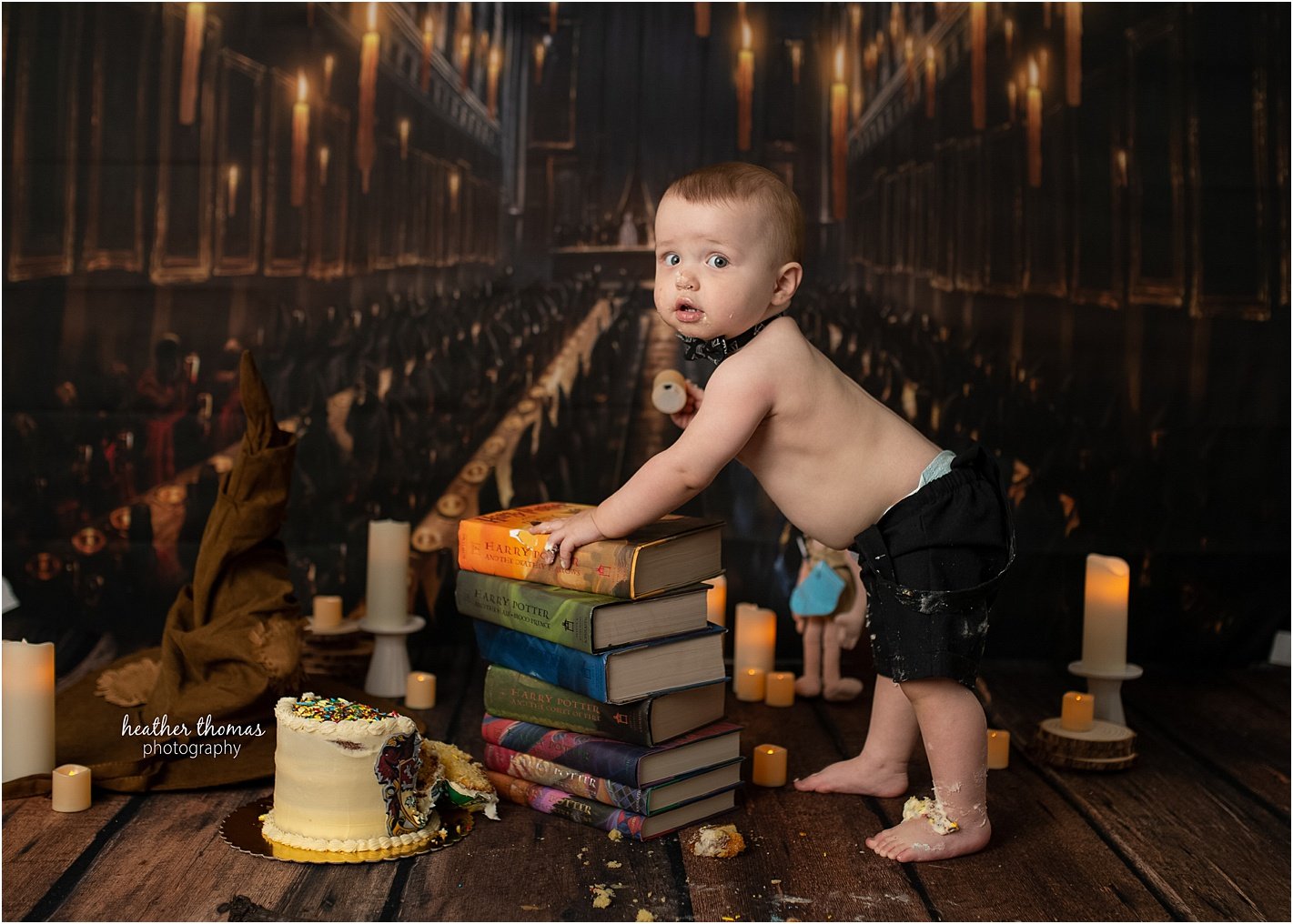 outdoor photography session newtown pa Toddler boy smashing Harry Potter birthday cake while mom and dad smile during family photo session in Philadelphia