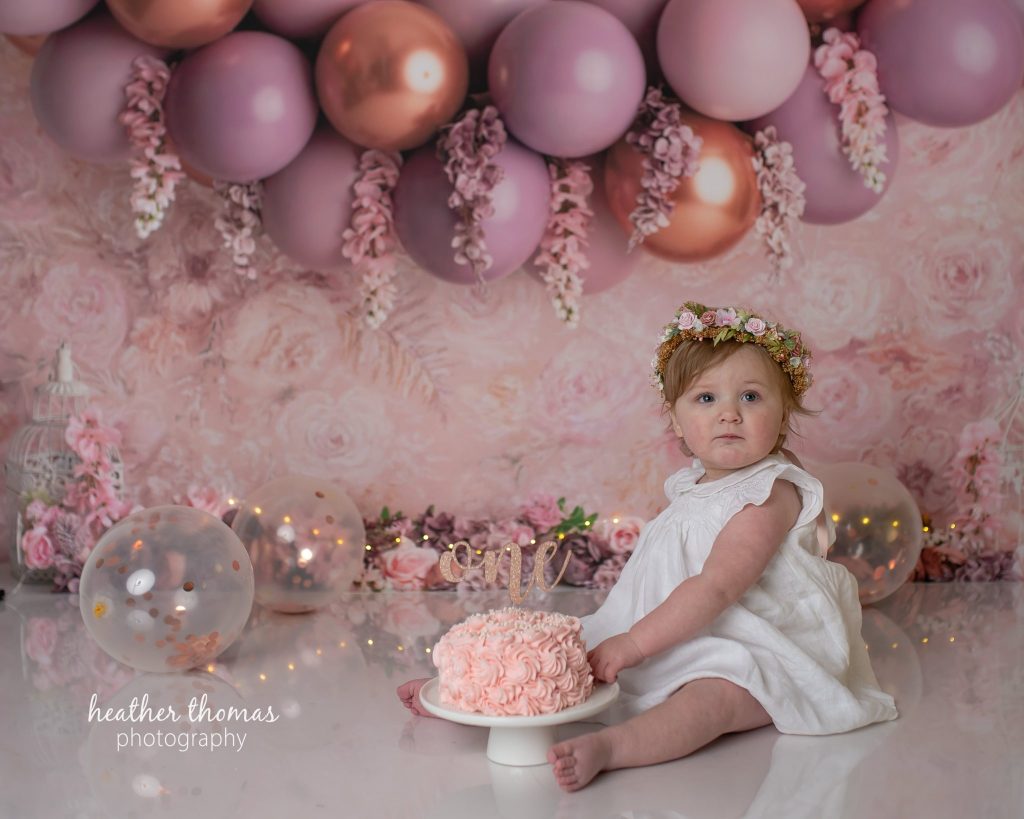 5 Things To#15 Ask Before Your Cake Smash Shoot | Bucks County Family Photographer little one sits under balloons in pink studio by Bucks County Family Photographer