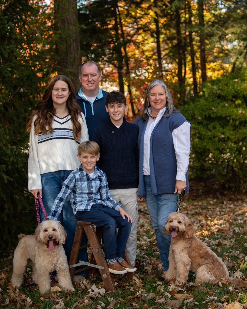 When to Book a Fall Photo Session in Bucks County PA a Family of 5 standing in a colorful fall foliage in Bucks County PA during autumn photo session